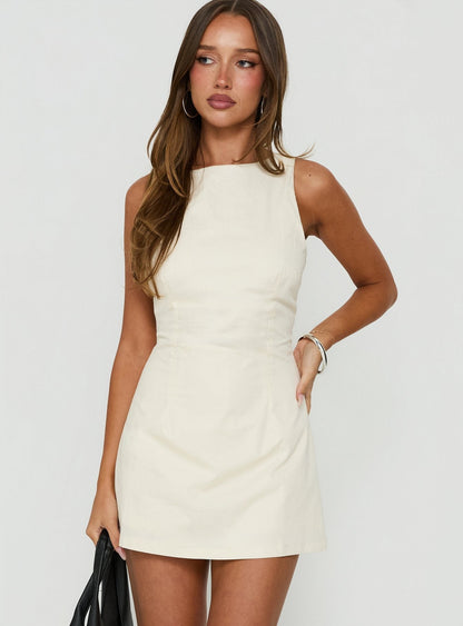 Model wearing a cream sleeveless playsuit with a high round neck and built-in shorts