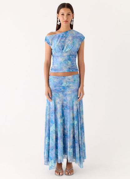 Model wearing a blue paisley print low-rise ruched maxi skirt with a matching cap sleeve top