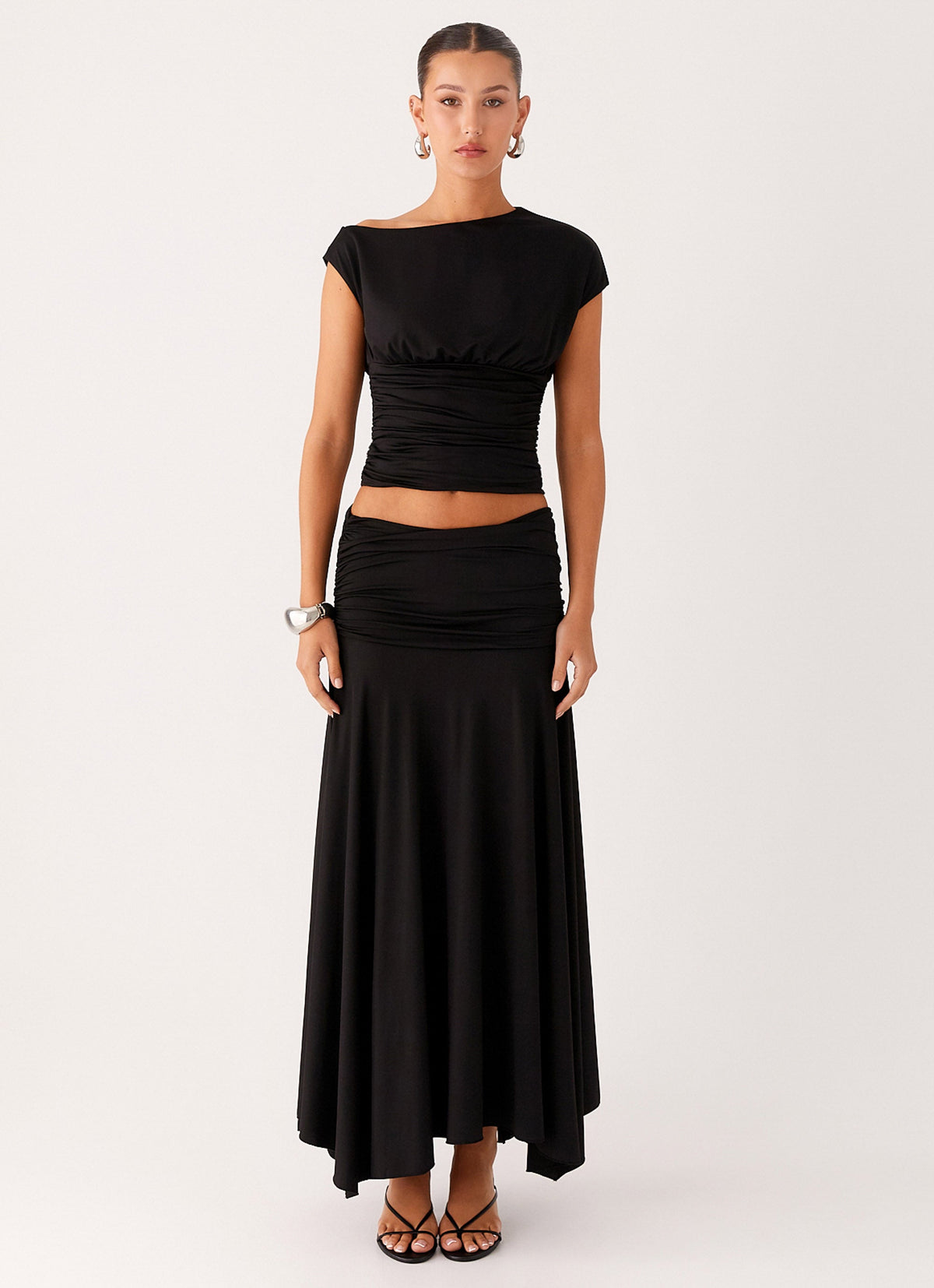 Full length view of a model wearing the black low-rise ruched maxi skirt