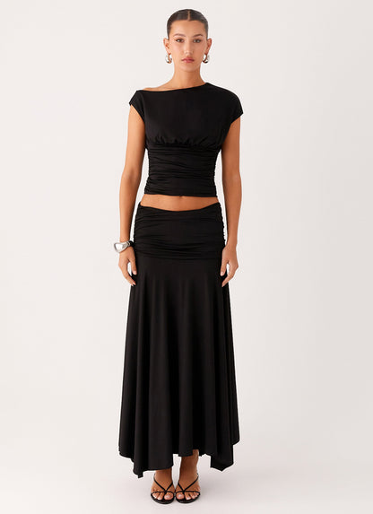 Full length view of a model wearing the black low-rise ruched maxi skirt