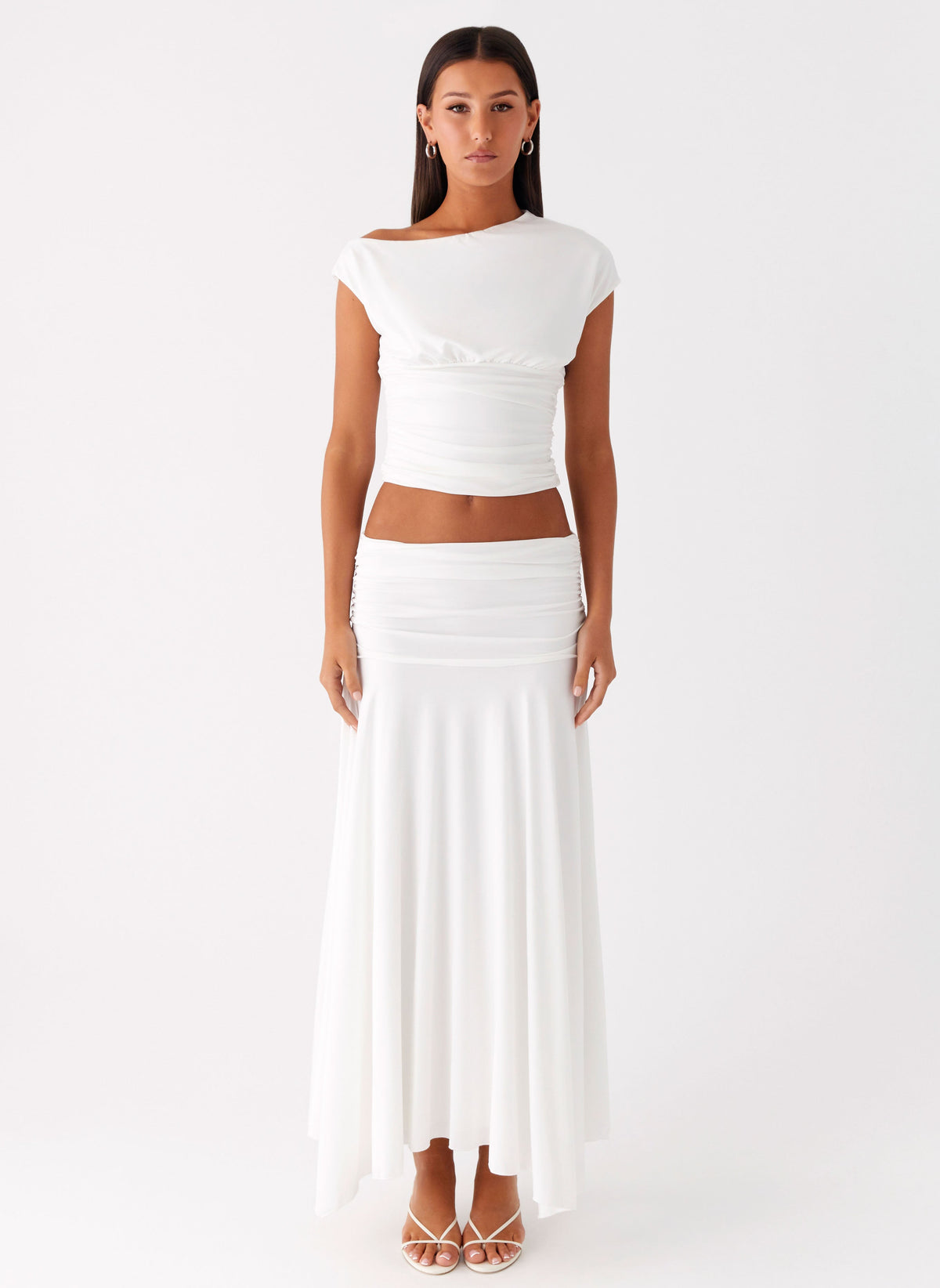Full length view of a model wearing the white low-rise ruched maxi skirt