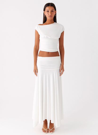 Full length view of a model wearing the white low-rise ruched maxi skirt