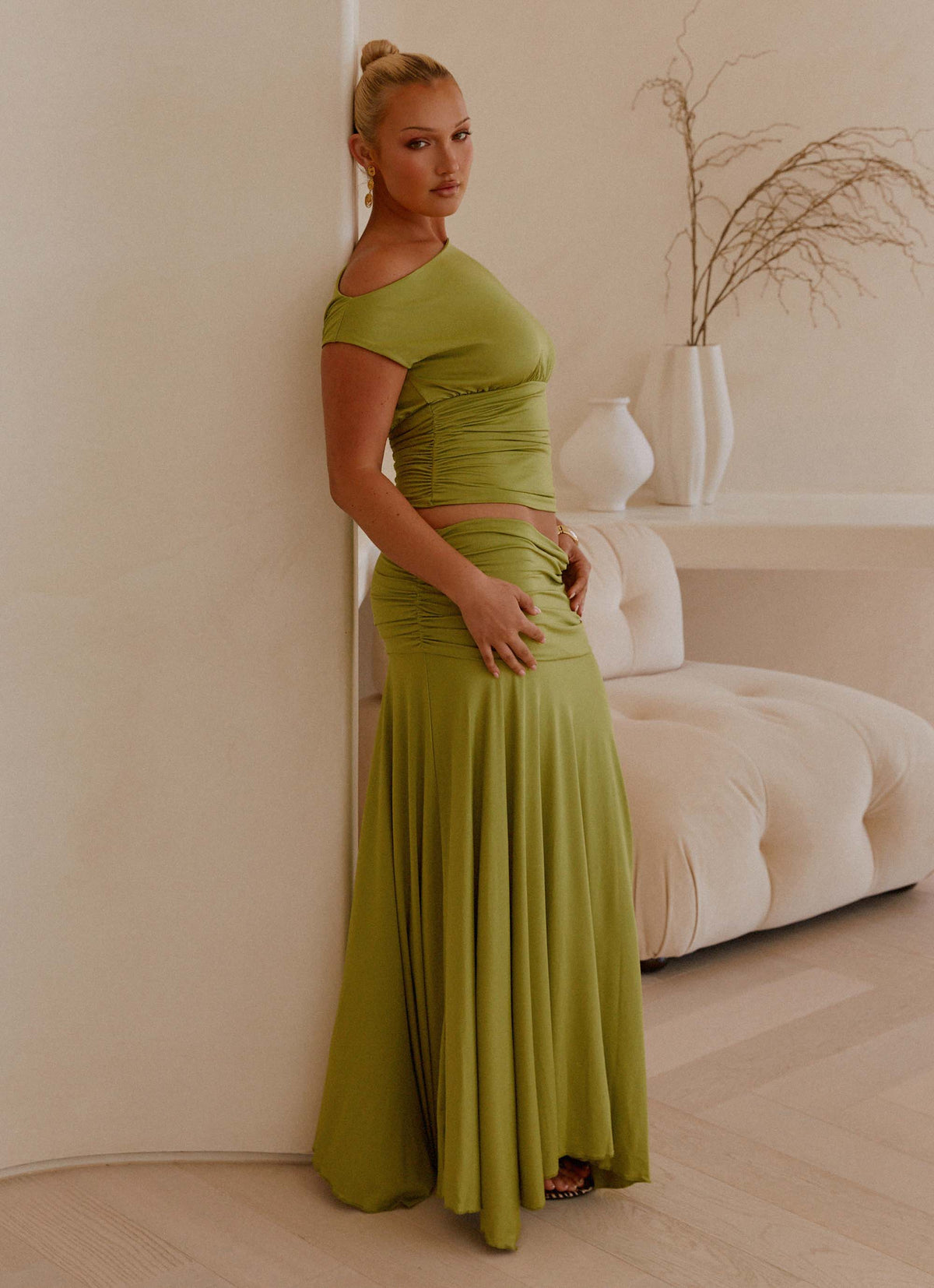 Side view of the green ruched maxi skirt showing the gathered low-rise waist and flared hem