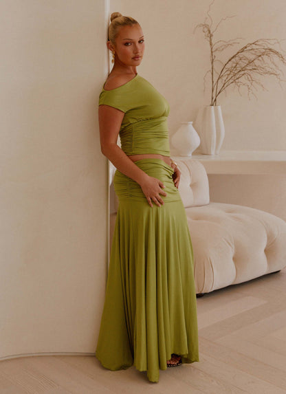 Side view of the green ruched maxi skirt showing the gathered low-rise waist and flared hem