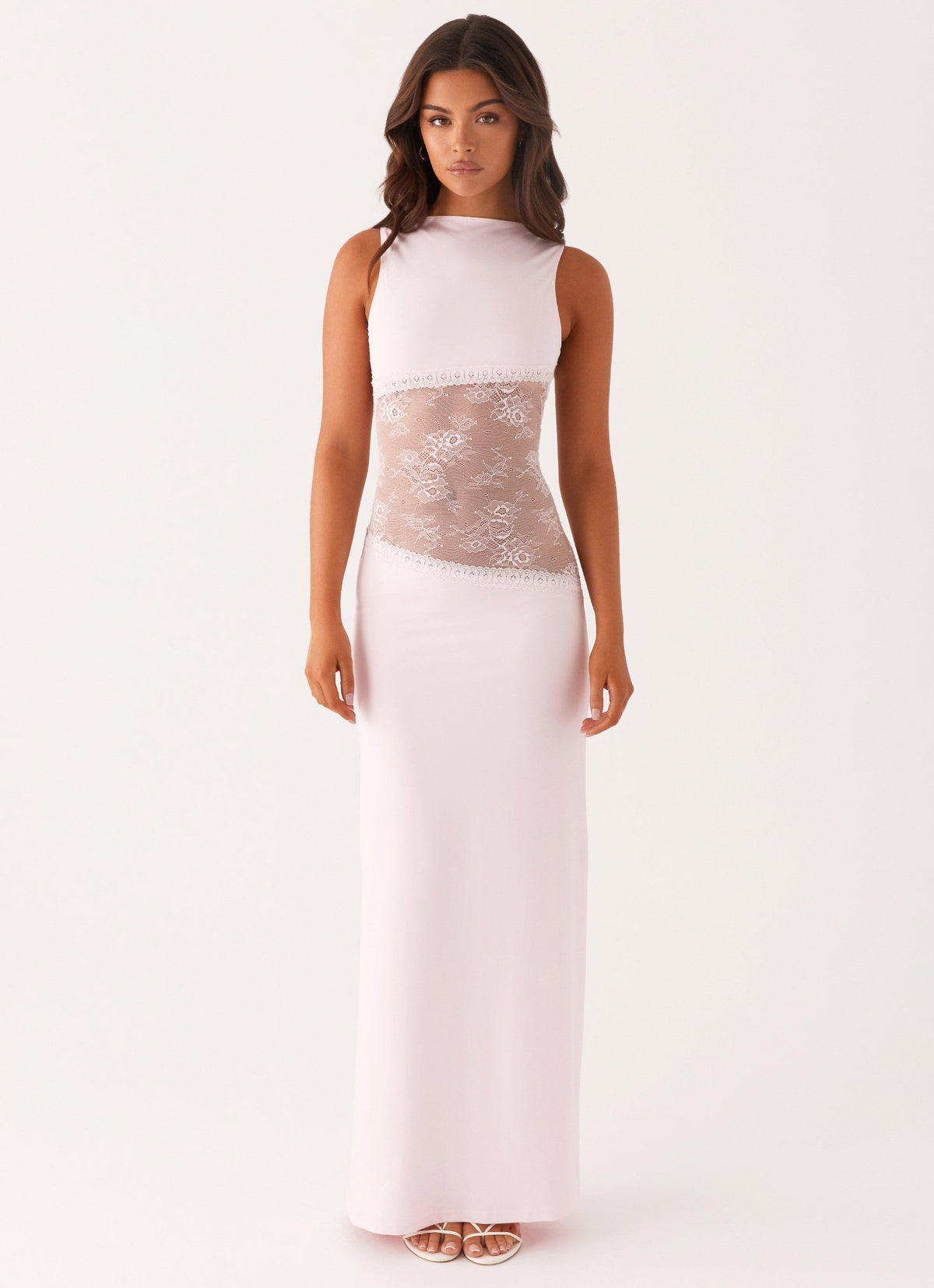 Model wearing a pale pink jersey maxi dress with a high round neck and a diagonal sheer lace waist panel
