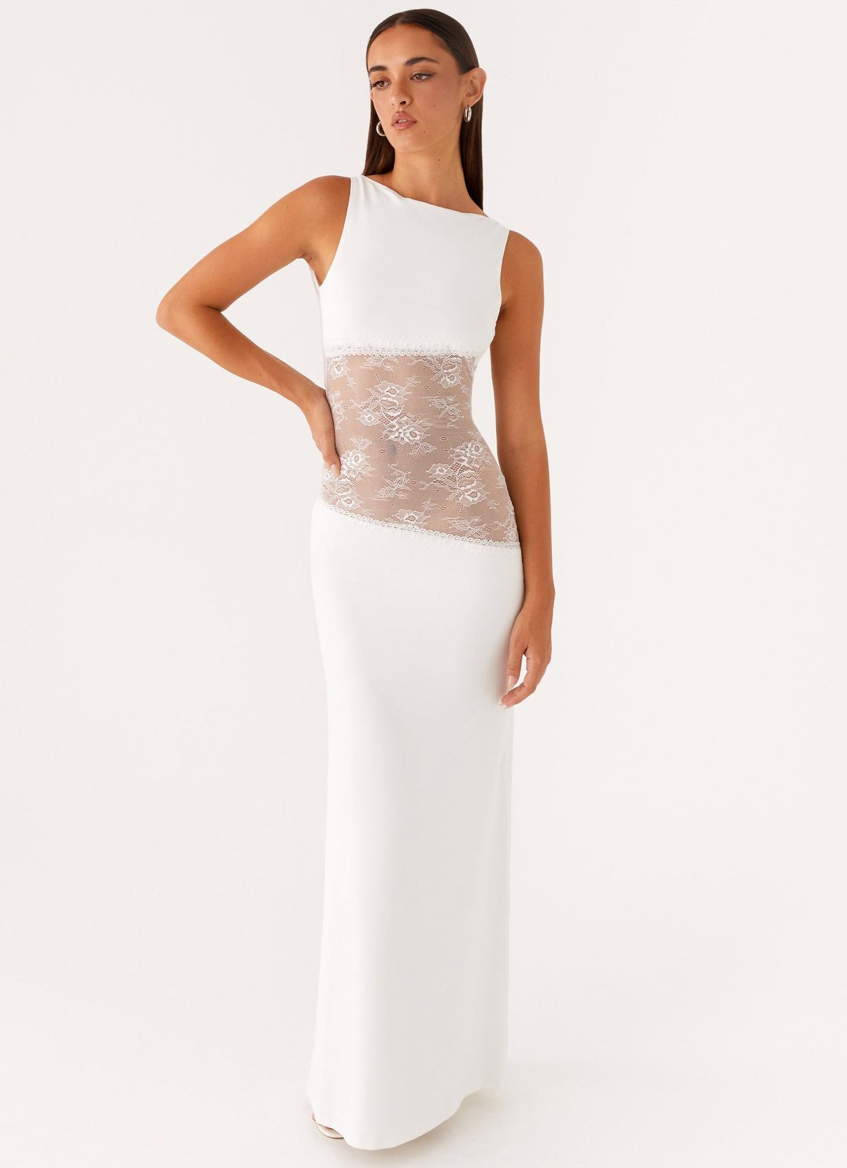 Model wearing a white jersey maxi dress with a high round neck and a diagonal sheer lace waist panel