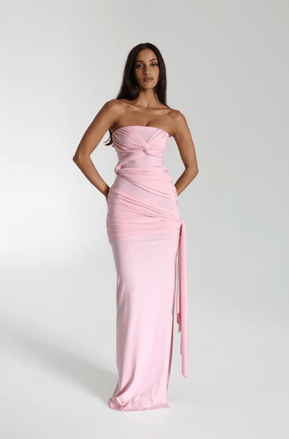 Model wearing a blossom pink strapless maxi gown with a knotted bust and draped side tie