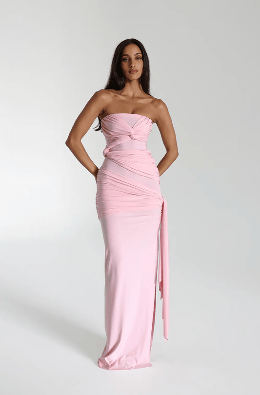 Model wearing a blossom pink strapless maxi gown with a knotted bust and draped side tie