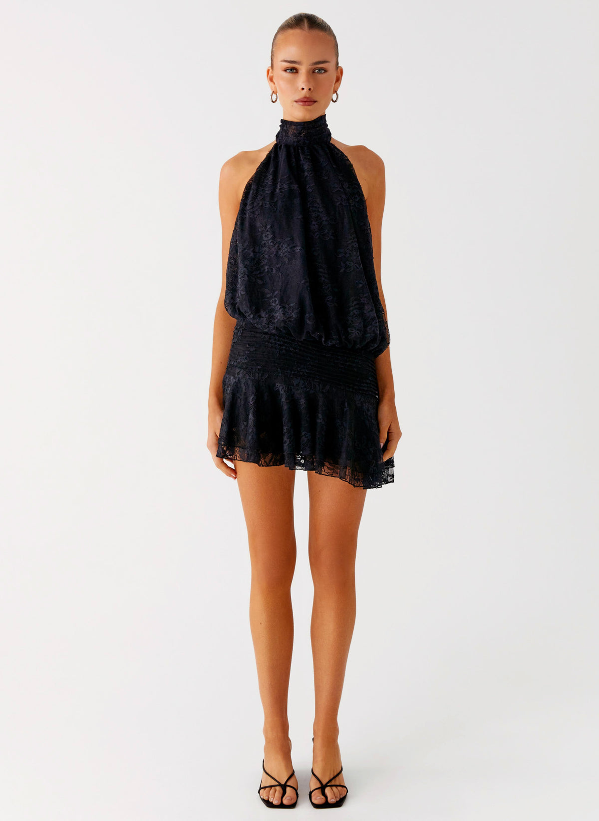 Back view of the black lace halter neck mini dress showing the open back and tie neck strap