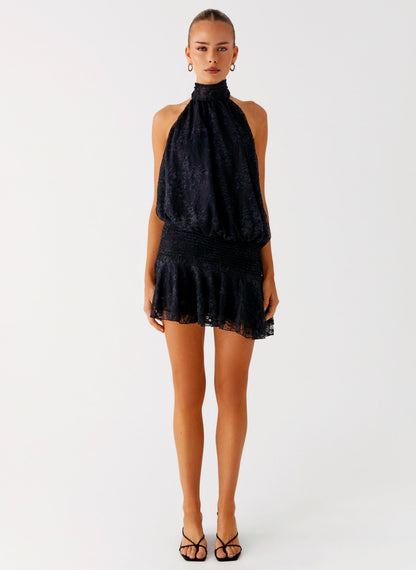 Back view of the black lace halter neck mini dress showing the open back and tie neck strap