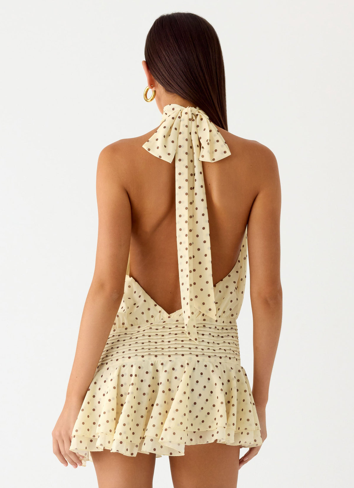 Back view of the yellow polka dot halter neck mini dress showing the open back and tie neck strap