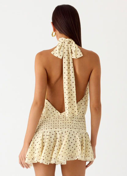 Back view of the yellow polka dot halter neck mini dress showing the open back and tie neck strap