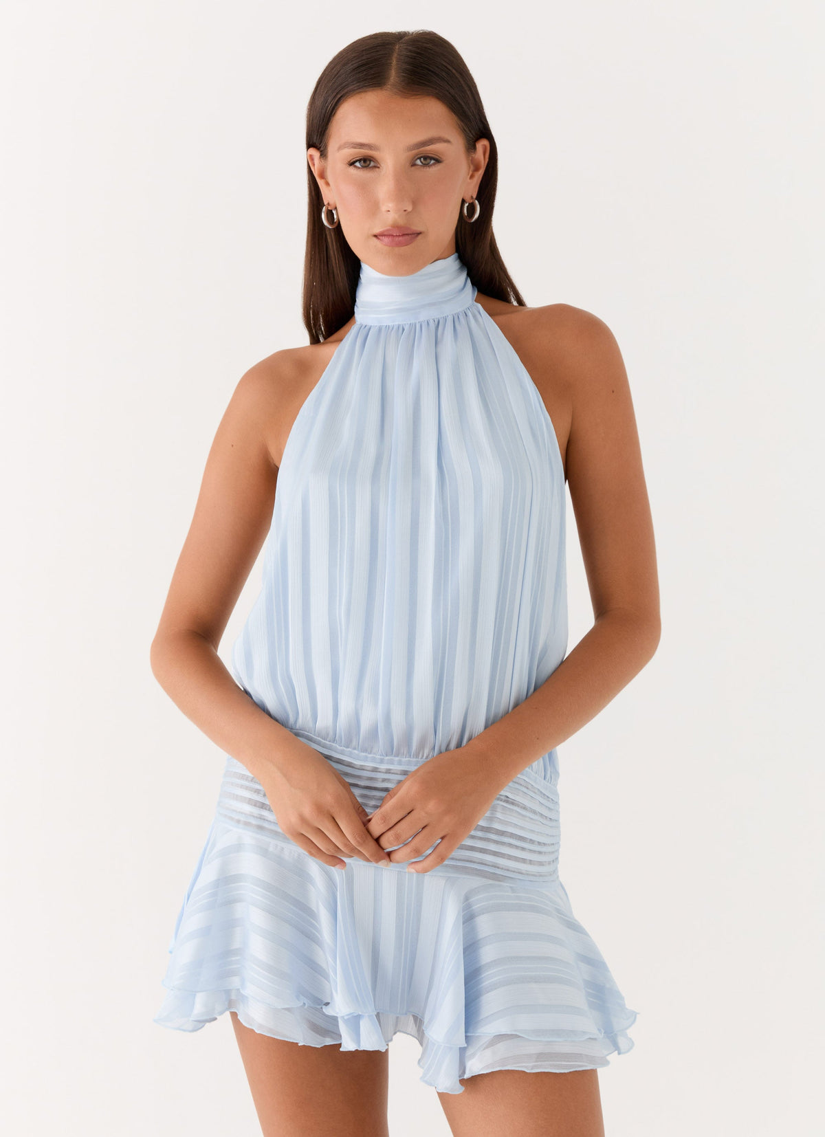 Model wearing a light blue chiffon halter neck mini dress with a pleated drop waist and flared hem