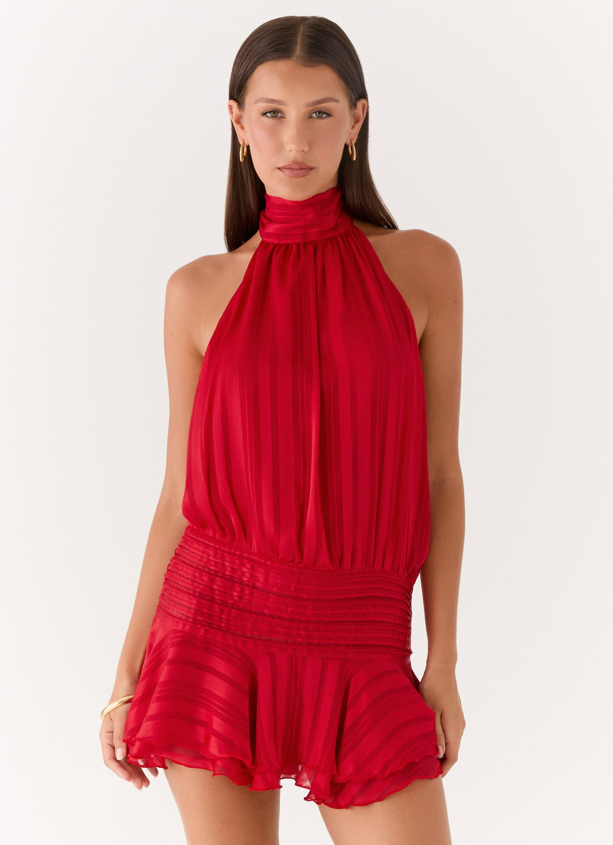 Model wearing a red chiffon halter neck mini dress with a pleated drop waist and tiered flared hem