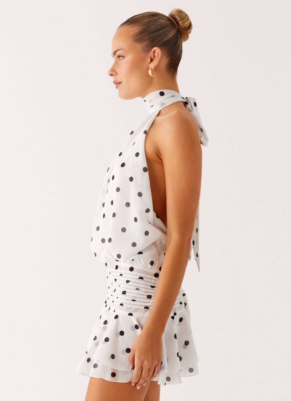Side view of the white polka dot chiffon halter neck mini dress showing the drop waist and flared hem